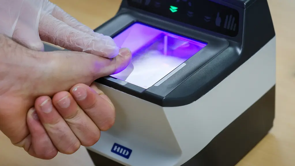 Auf dem Foto zu sehen ein Gerät, das die Fingerabdrücke einer Person erfasst. 