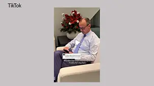 Kanzler Merz schaut in seinem Büro auf ein Smartphone in seiner Hand.