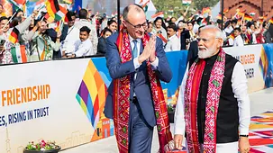 Le chancelier Friedrich Merz faisant le geste de salut Namasté au côté de Narendra Modi, le premier ministre indien.