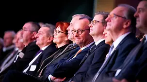 Das Foto zeigt Bundeskanzler Friedrich Merz im Publikum beim Neujahrsempfang der IHK Halle-Dessau