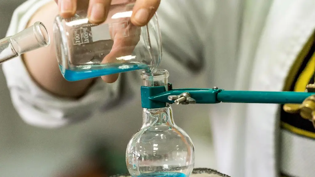 The photo shows a researcher in a laboratory with test tubes.