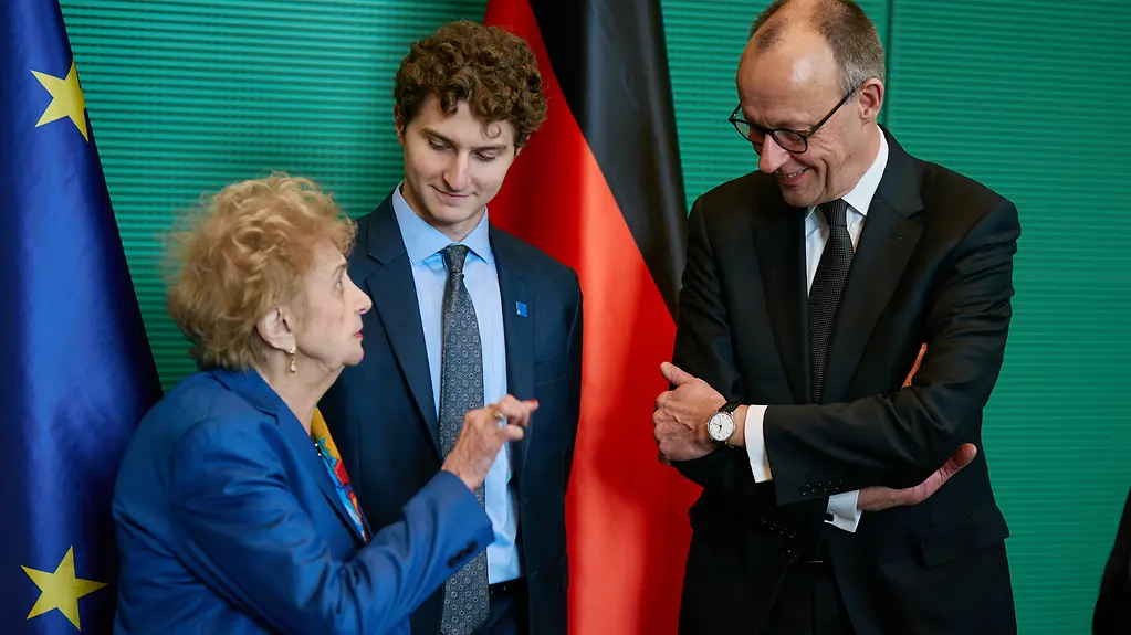 Tova Friedman mit ihrem Enkel und Bundeskanzler Merz bei der Gedenkstunde für die Opfer des Nationalsozialismus im Bundestag.