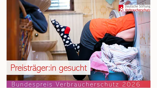 Bundespreis Verbraucherschutz 2026 - Preisträger:in gesucht, Frau steckt mit dem Oberkörper in einer Waschmaschine, davor steht ein Korb mit Wäsche