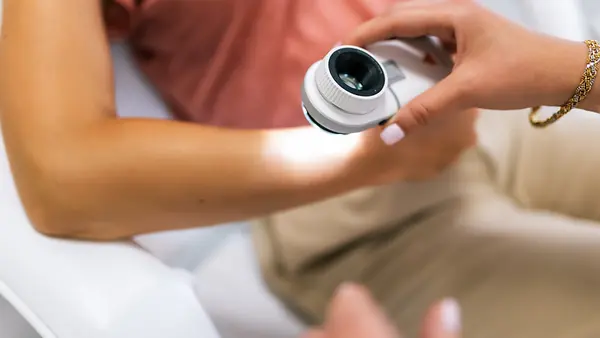Eine Dermatologin untersucht Muttermale einer Patientin mit einem Dermatoskop.