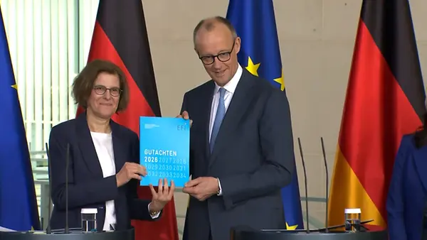 Bundeskanzler Friedrich Merz und Frau Prof. Bertschek halten zusammen das Gutachten hoch. 