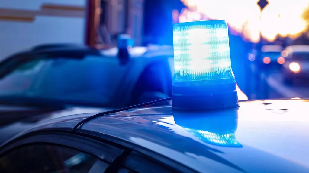 Gyrophare bleu allumé sur le toit d’un véhicule de police banalisé dans la pénombre