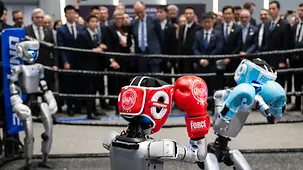 Le chancelier fédéral Friedrich Merz observant un combat de boxe entre robots.
