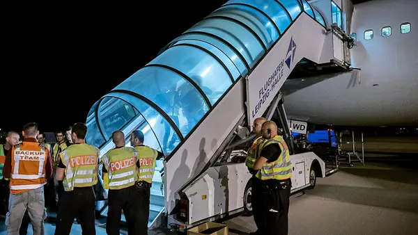 Polizeibeamte begleiten einen Afghanen auf dem Flughafen Leipzig-Halle in ein Charterflugzeug.