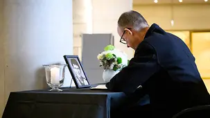 Das Foto zeigt Bundeskanzler Friedrich Merz beim Eintrag in das Kondolenzbuch von Rita Süssmuth im Bundestag.