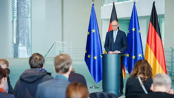Kanzler Merz vor Pressevertreterinnen und -vertretern am Rednerpult vor Flaggen im Kanzleramt.
