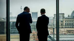 Bundeskanzler Friedrich Merz im Gespräch mit Andrej Babiš an einem Fenster im Bundeskanzleramt.
