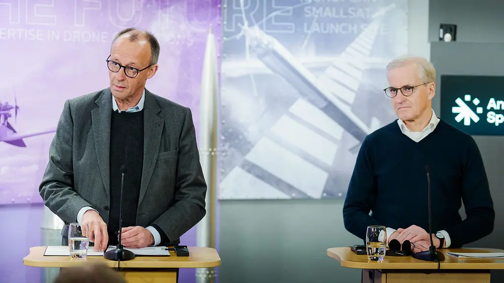 Bundeskanzler Merz und der norwegische Ministerpräsident Støre hinter Rednerpulten. Im Hintergrund Poster des Weltraumzentrums Andøya.