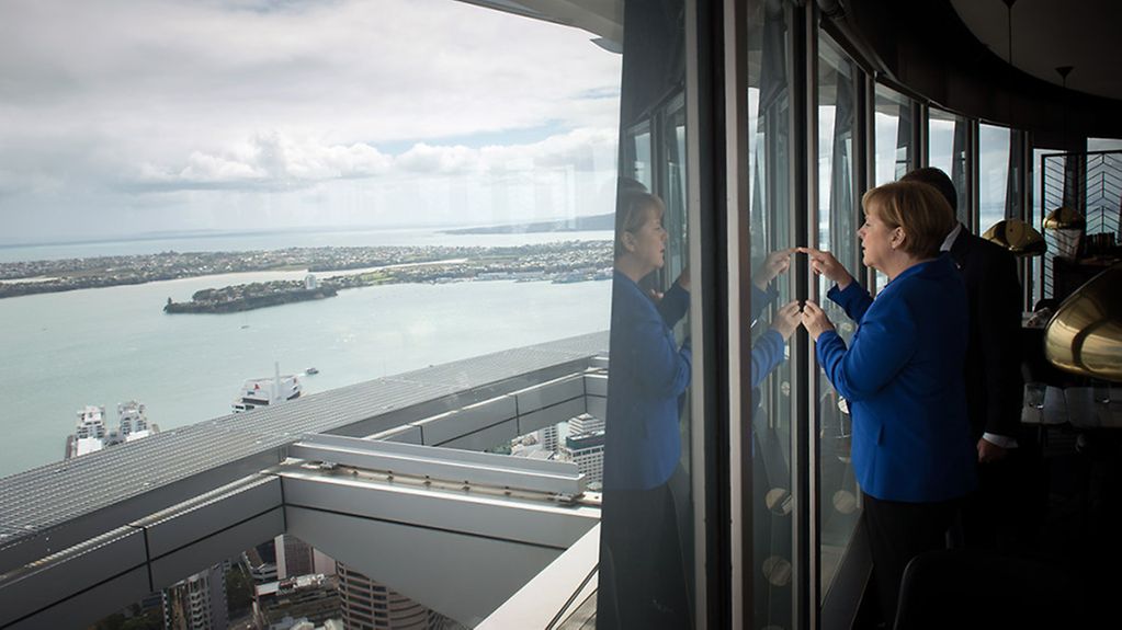 Merkel steht am Fenster mit Blick aufs Meer, neben ihr der neuseeländische Premierminister Key