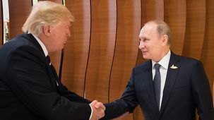 US-Präsident Donald Trump und der russische Präsident Wladimir Putin begrüßen sich vor Beginn des Retreats.