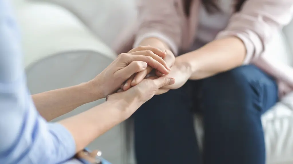 Nahaufnahme von vier Frauenhänden, die sich berühren.