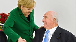 Chancellor Angela Merkel congratulates former Chancellor Helmut Kohl at a celebration to mark his 80th birthday.