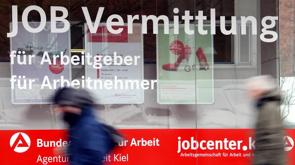 Passanten gehen am Schaufenster des Jobcenters der Bundesanstalt für Arbeit entlang.