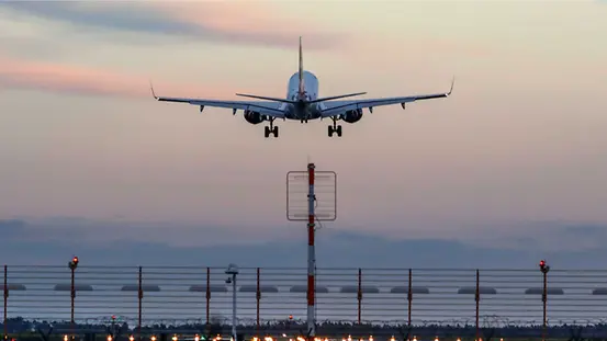 Abflug eines Flugzeugs von einem Flughafen vor einem Abendhimmel.