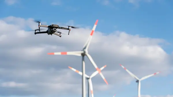 Eine Drohne fliegt in der Nähe eines Windparks.