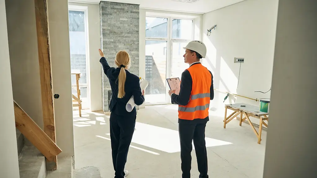 Eine Architektin und ein Bauingenieur besichtigen eine im Bau befindliche Wohnung.