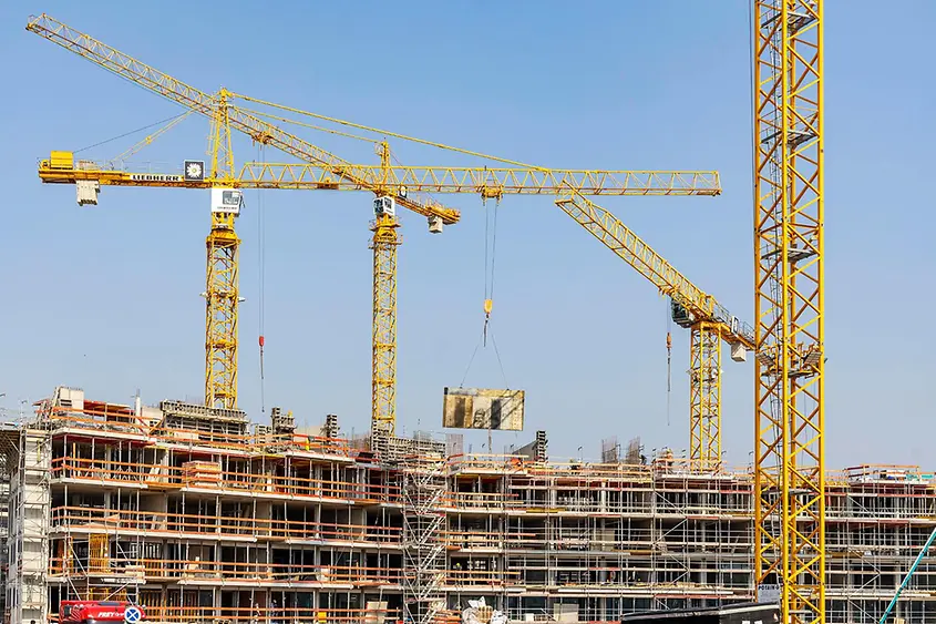 Ein Haus wird gebaut, Kräne sind zu sehen. 