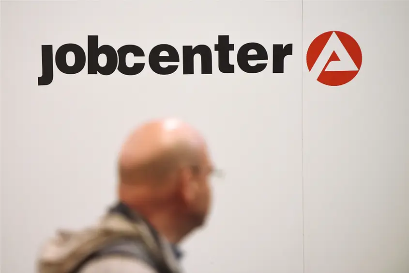 Logo des Jobcenters, darunter verschwommen eine Person.