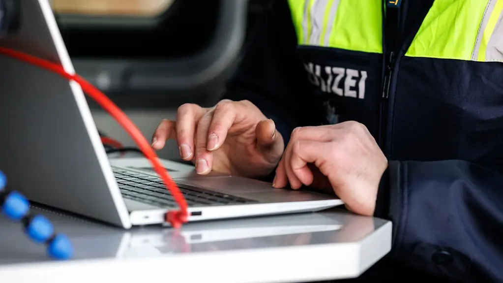 Polizeibeamter sitzt am Laptop.
