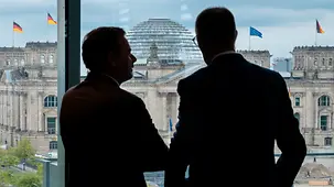 Schattenriss des Gesprächs von Bundeskanzler Friedrich Merz und Luis Montenegro, Portugals Premierminister, an einem Fenster des Kanzleramtes mit BLick auf das Reichstagsgebäude.