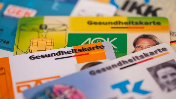  Mehrere Gesundheitskarten von verschiedenen Krankenkassen liegen zusammen 
