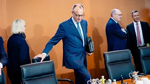Bundeskanzler Friedrich Merz setzt sich auf einen Stuhl am Kabinettstisch.