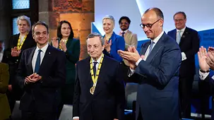 Bundeskanzler Friedrich Merz applaudiert neben Mario Draghi und weiteren Personen bei der Verleihung des Karlspreises.