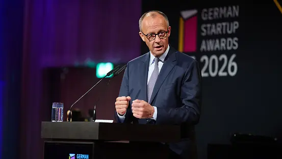 Bundeskanzler Merz hinter einem Rednerpult. Im Hintergrund der Schriftzug "German Startup Awards 2026".