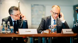 Bundeskanzler Friedrich Merz telefoniert an einem Schreibtisch neben Thorsten Frei, Chef des Bundeskanzleramtes und Bundesminister für besondere Aufgaben.