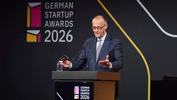 Bundeskanzler Merz hinter einem Rednerpult. Im Hintergrund der Schriftzug "German Startup Awards 2026".