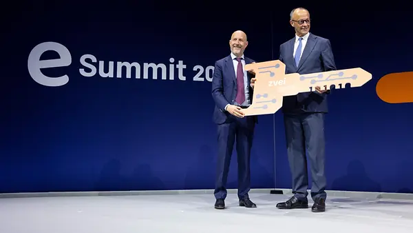 Bundeskanzler Friedrich Merz (r.) erhält einen Schlüssel beim eSummit des Verbandes der Elektro- und Digitalindustrie (ZVEI) im Gasometer auf dem Euref-Campus (l. Daniel Hager, ZVEI-Präsident)