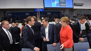 Chancellor Angela Merkel talks with Greek Prime Minister Alexis Tsipras and French President Emmanuel Macron at the start of the working dinner.