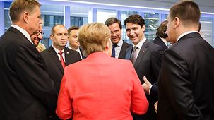 Chancellor Angela Merkel speaks with other participants in the Leaders' Lounge on her arrival in Brussels.