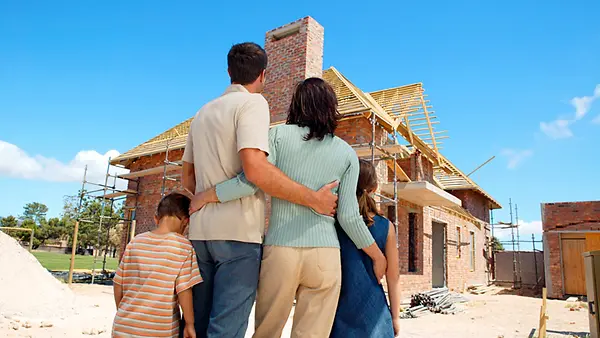 Eine Familie steht vor der Baustelle eines Einfamilienhauses