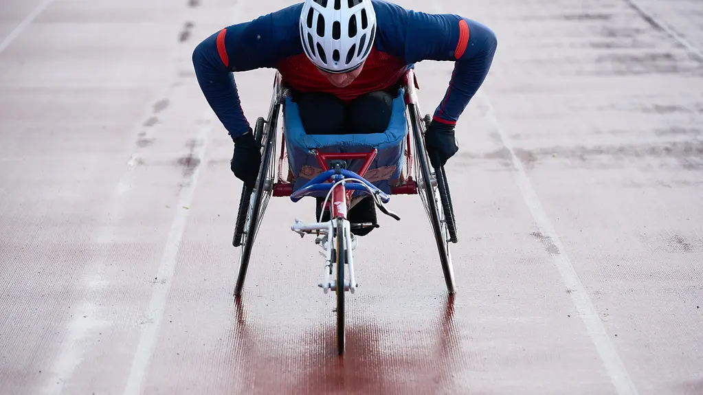 Paraplegic male athlete training speed while racing in sport wheelchair 