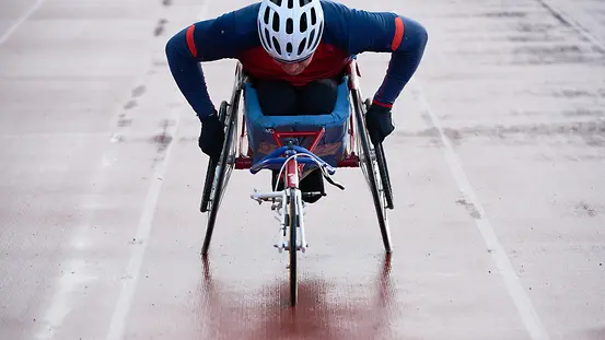 Paraplegic male athlete training speed while racing in sport wheelchair 