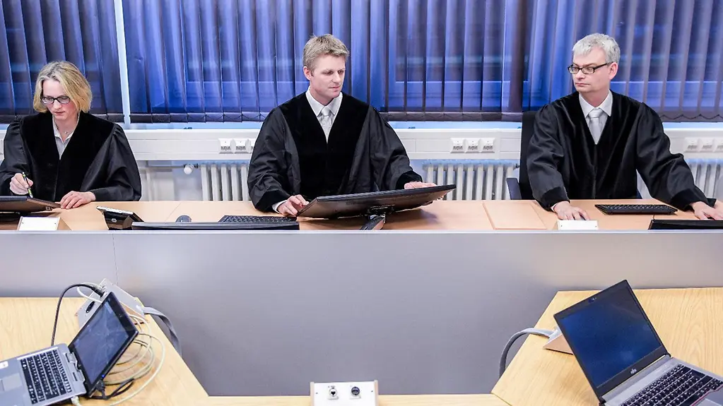 Richter sitzen bei der Präsentation des digitalen Gerichtssaals am Richtertisch