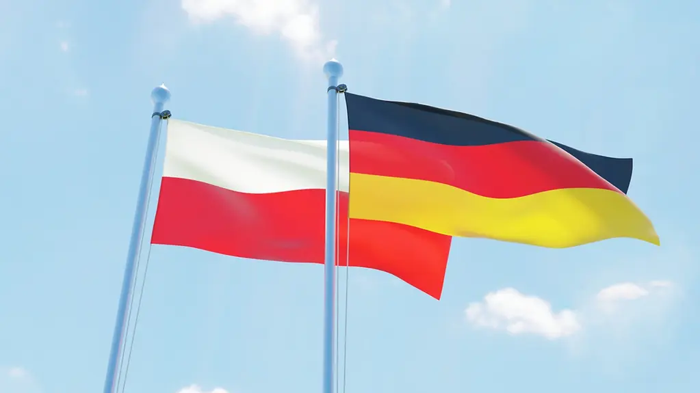 The flags of Germany and Poland against a blue sky.