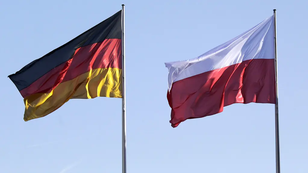 Die Flaggen von Deutschland und Polen vor blauem Himmel. 