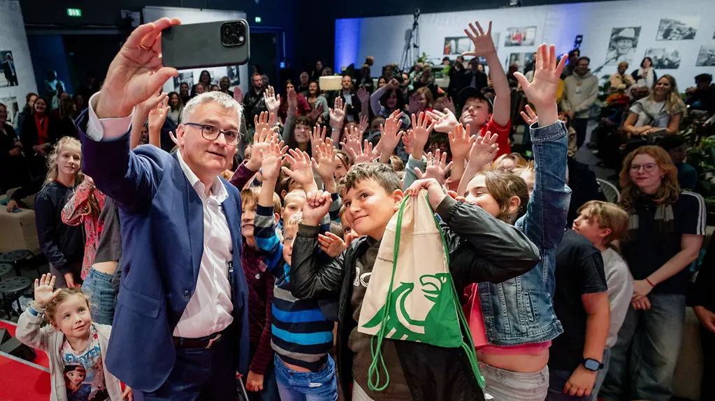 Regierungssprecher Stefan Kornelius beim Selfie mit Teilnehmerinnen und Teilnehmern einer Kinder- und Jugendpressekonferenz am Tag der offenen Tür der Bundesregierung 2025