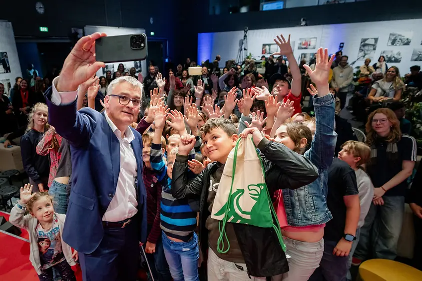 Regierungssprecher Stefan Kornelius beim Selfie mit Teilnehmerinnen und Teilnehmern einer Kinder- und Jugendpressekonferenz am Tag der offenen Tür der Bundesregierung 2025