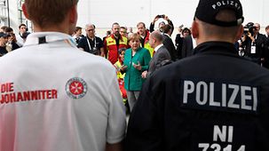Bundeskanzlerin Angela Merkel im Gespräch mit Sicherheitskräften des G20-Gipfels (daneben Olaf Scholz, Erster Bürgermeister von Hamburg).