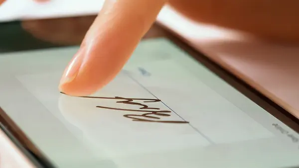 Nahaufnahme einer digitalen Unterschrift auf einem Bildschirm mit einer Hand.