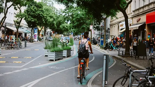 Eine Frau die an einem sonnigen Sommertag im Berliner Stadtteil Neukölln, in der Nähe von Kreuzberg, mit dem Fahrrad unterwegs ist. 