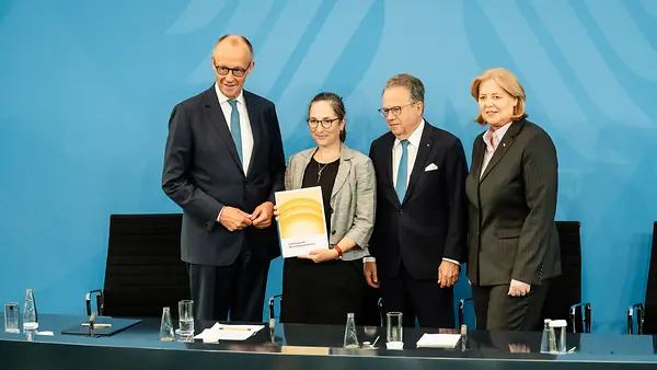 Bundeskanzler Merz und Ministerin Bas stehen mit Frank-Jürgen Weise und Constanze Janda in der Regierungspressekonferenz und halten den Bericht der Alterssicherungskommission in den Händen.
