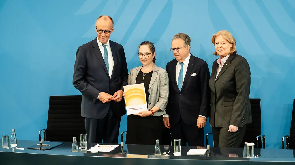Federal Chancellor Merz and Minister Bas stand alongside Frank-Jürgen Weise and Constanze Janda at the Government press conference, holding the report by the Pensions Commission.